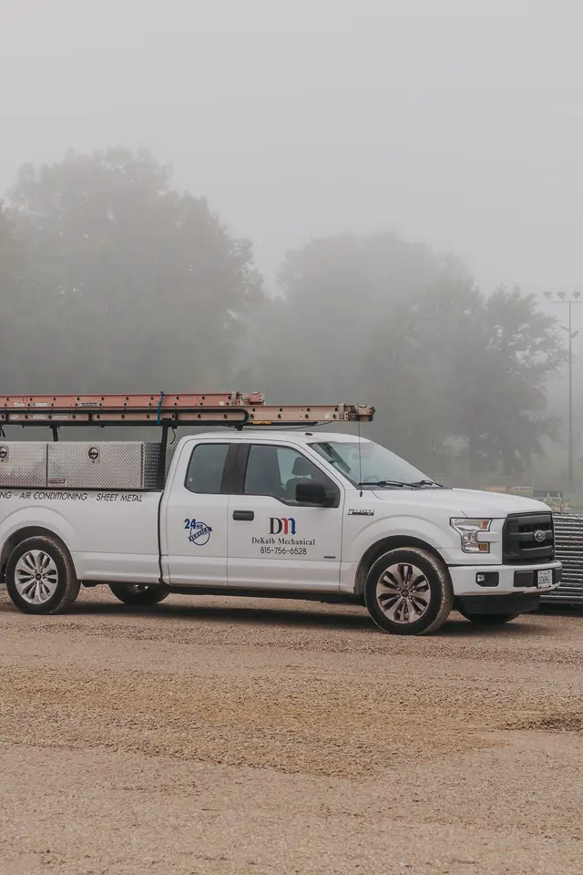 A DeKalb Mechanical service pickup lettered 24HR SERVICE, on a foggy DeKalb morning