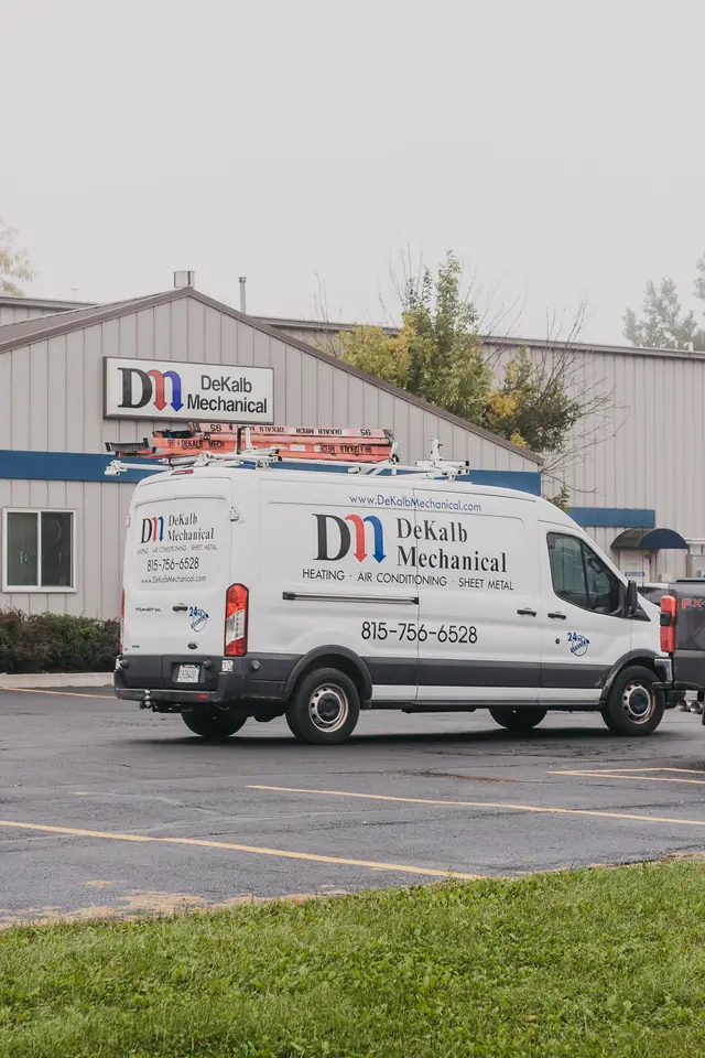 A DeKalb Mechanical service van parked outside the company's own building on Wurlitzer Drive, with the DM shop signage behind it