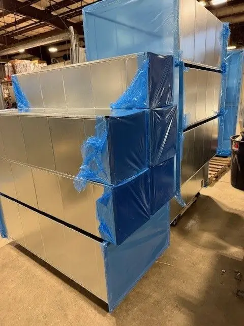 Coil-line duct fabrication in progress, with wrapped finished units standing on the shop floor