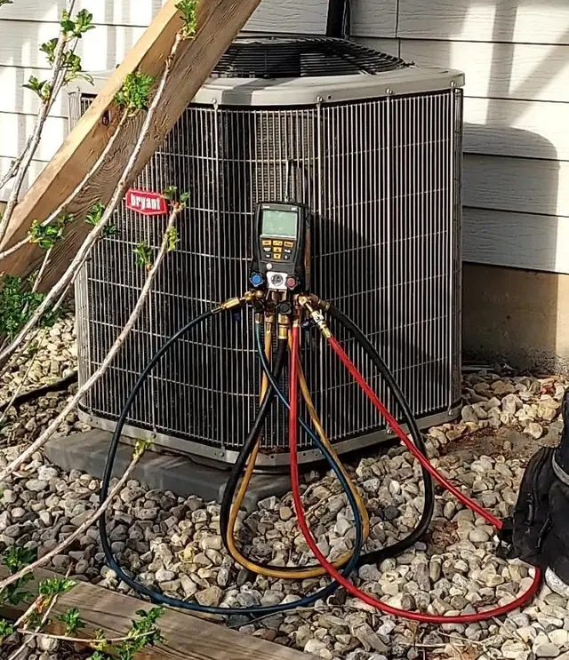 A Bryant residential condenser with digital refrigerant gauges connected during a diagnostic
